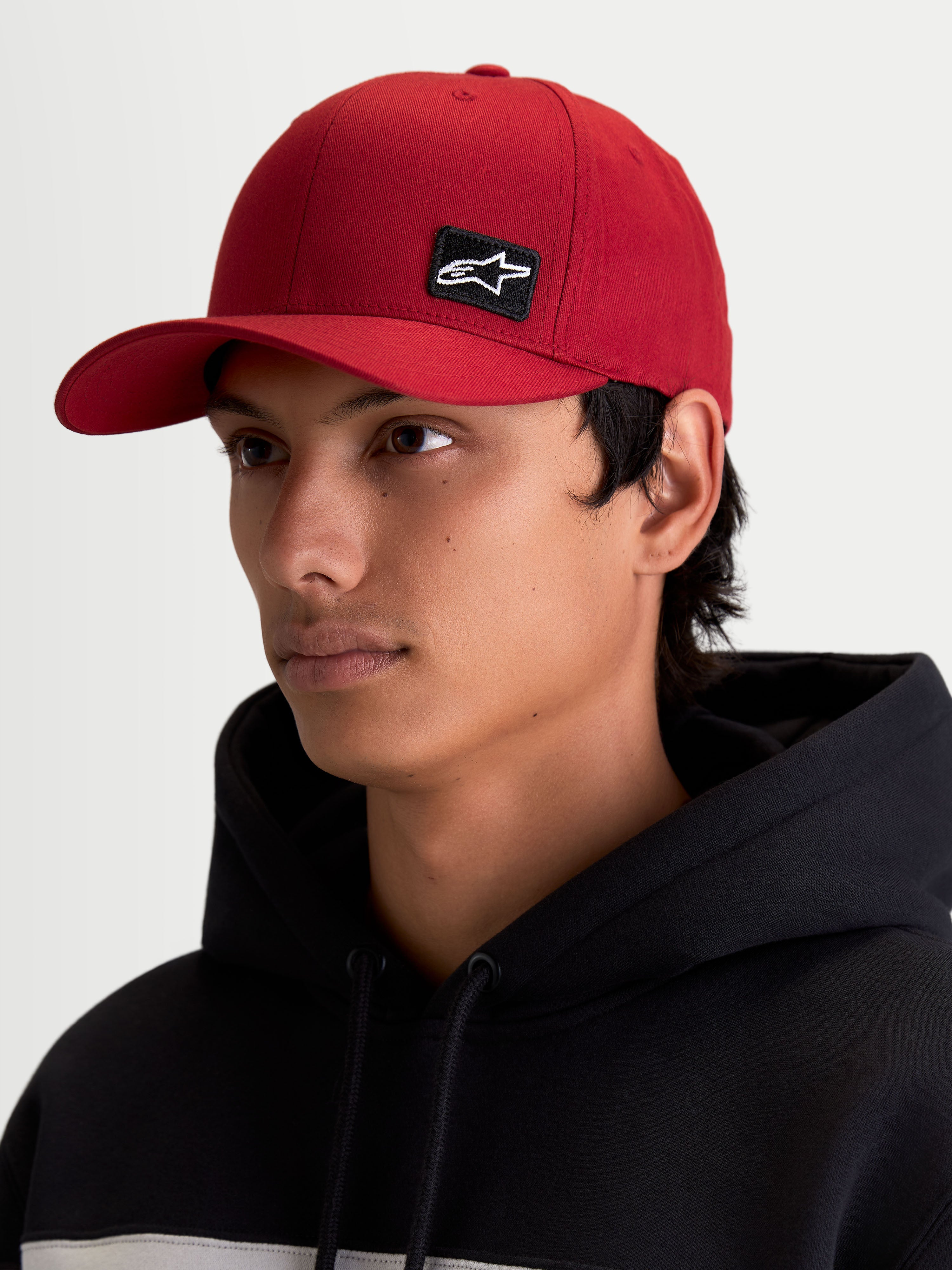Alpinestars Czapka Pivot, czerwona lifestyle'owa czapka z daszkiem unisex, zakrzywiony daszek, usztywniona korona, mała czarna haftowana naszywka z logo Astars, widok na modelu.