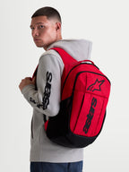 Alpinestars Plecak GFX Boss, miejski plecak sportowy, czerwony i czarny, silikonowa grafika Astars, pojemność 20l, wewnętrzna kieszeń na laptopa, model w szarej bluzie z kapturem, wytrzymały poliester 600D