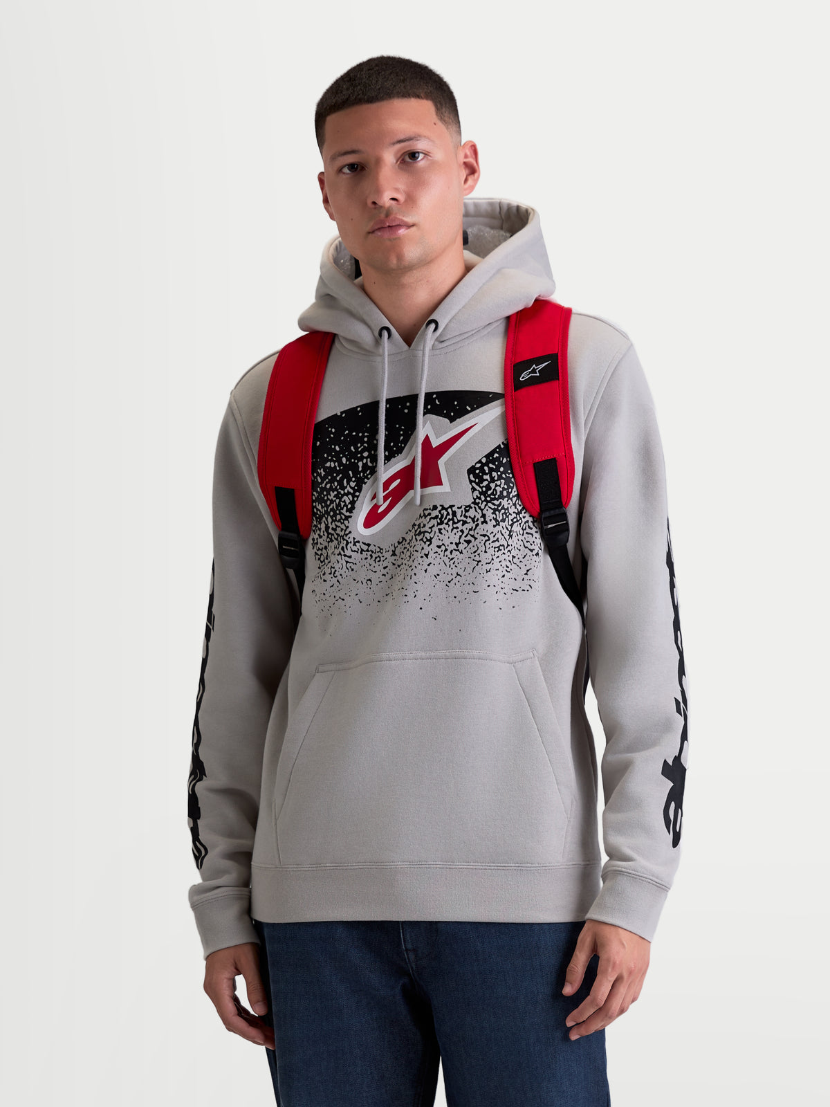 Alpinestars Plecak GFX Boss, sportowy plecak miejski o pojemności 20 l, męski i damski, czerwony i czarny, wykonany z wytrzymałego poliestru 600D, widok z przodu na modelu, regulowane ramiączka z siatki i wypukłe silikonowe logo.