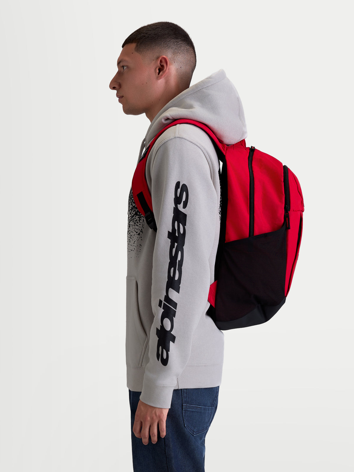 Alpinestars plecak GFX Boss, miejski plecak sportowy o pojemności 20l, czerwony i czarny, wykonany z wytrzymałego poliestru 600D, boczne siatkowe kieszenie na butelkę i wyściełane ramiączka, widoczny na modelu, idealny do codziennego użytku i miejskich dojazdów.