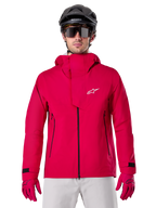 Alpinestars A-Dura Elite Waterproof Jacket, kurtka przeciwdeszczowa MTB, czerwony fluo, wysoki kołnierz z białym logo Alpinestars, czarne detale zamków, noszona z pasującymi rękawicami i czarnym kaskiem rowerowym, techniczna wodoodporna odzież rowerowa