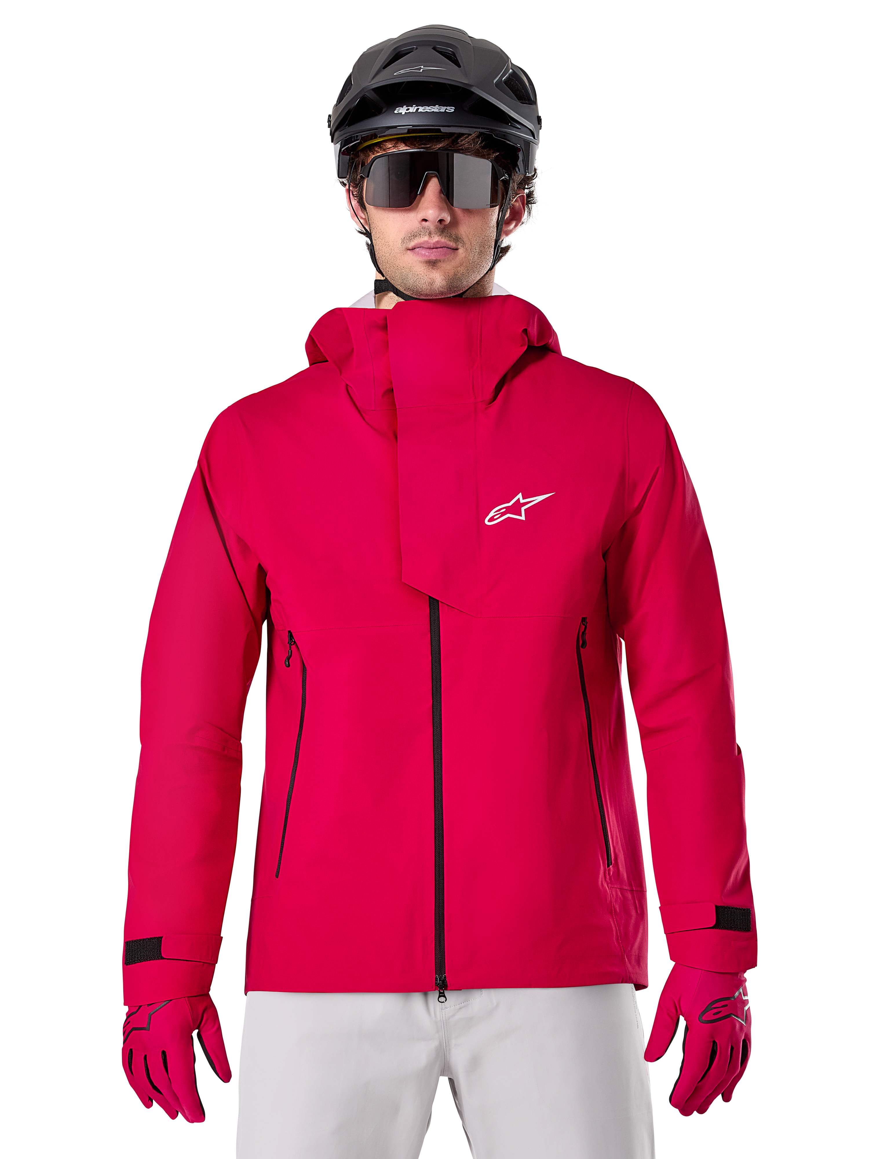 Alpinestars A-Dura Elite Waterproof Jacket, kurtka przeciwdeszczowa MTB, czerwony fluo, wysoki kołnierz z białym logo Alpinestars, czarne detale zamków, noszona z pasującymi rękawicami i czarnym kaskiem rowerowym, techniczna wodoodporna odzież rowerowa