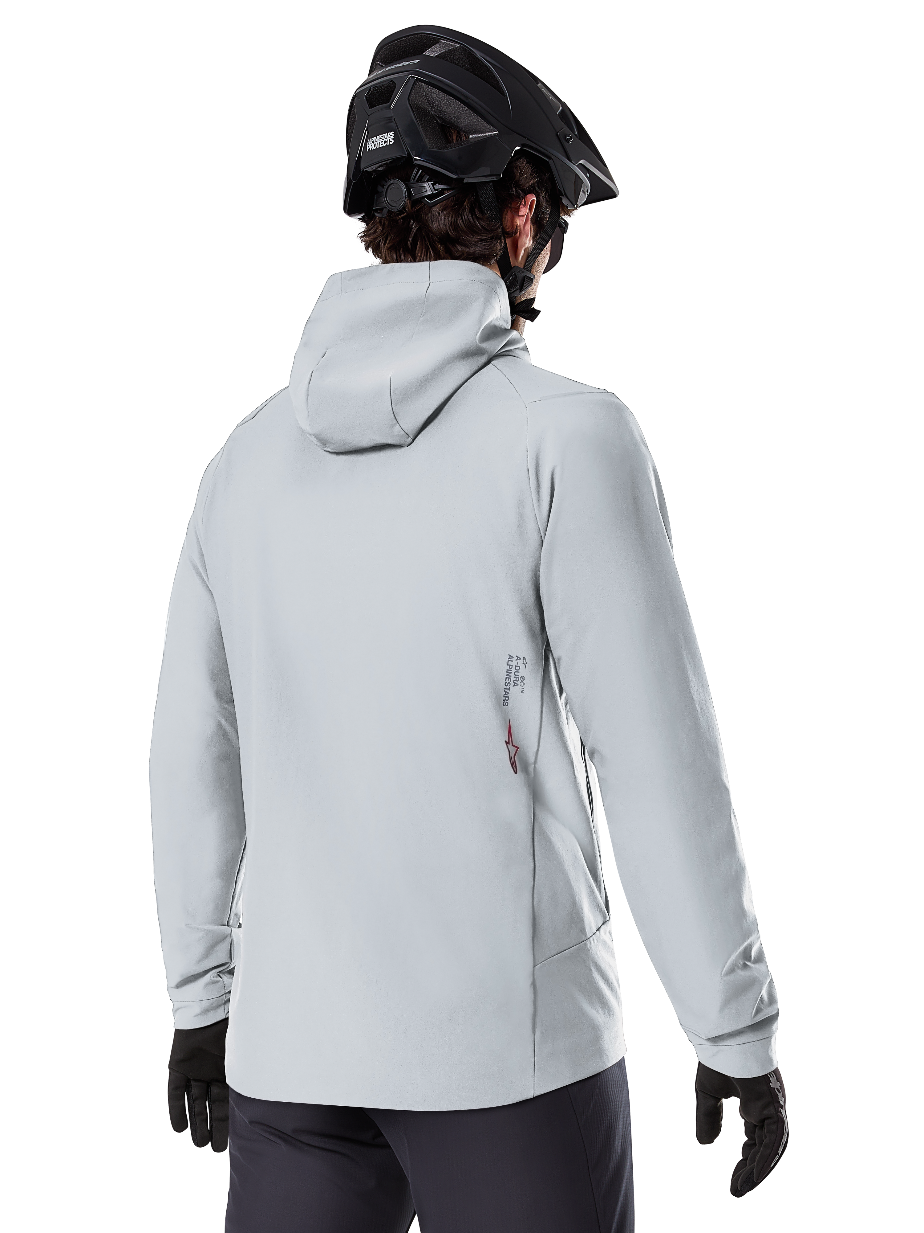 Kurtka Alpinestars A-Dura Thermal, Titanium Gray, widok od tyłu rowerzysty w ocieplanej kurtce z kapturem, w zestawieniu z czarnym kaskiem MTB i czarnymi rękawiczkami, małe logo Alpinestars na dole pleców, zaprojektowana do jazdy MTB w niskich temperaturach