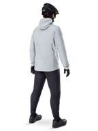 Alpinestars A-Dura Thermal Jacket w kolorze Titanium, widok od tyłu na rowerzystę ubranego w jasnoszarą kurtkę termiczną z kapturem, czarny kask MTB, czarne rękawiczki i ciemnoszare spodnie, funkcjonalna odzież do jazdy na rowerze górskim