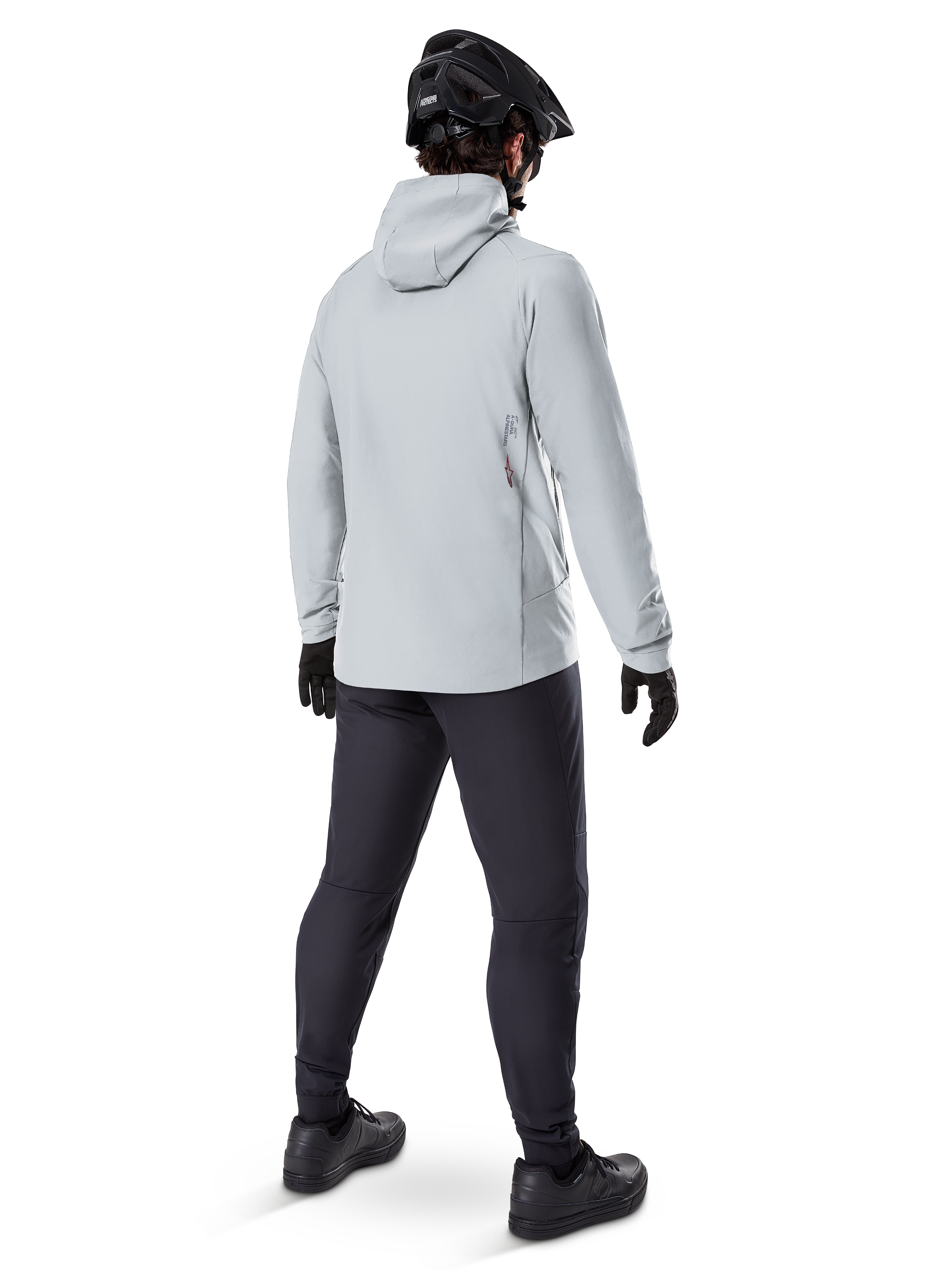 Alpinestars A-Dura Thermal Jacket w kolorze Titanium, widok od tyłu na rowerzystę ubranego w jasnoszarą kurtkę termiczną z kapturem, czarny kask MTB, czarne rękawiczki i ciemnoszare spodnie, funkcjonalna odzież do jazdy na rowerze górskim