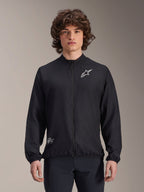 Alpinestars A-Aria Windbreaker Jacket, czarna, lekka kurtka rowerowa typu wiatrówka, z białym logo Astars na klatce piersiowej i brandingiem na dole po prawej stronie, pełny zamek, stójka, elastyczne mankiety i dolny brzeg, sportowy krój do aktywności na zewnątrz