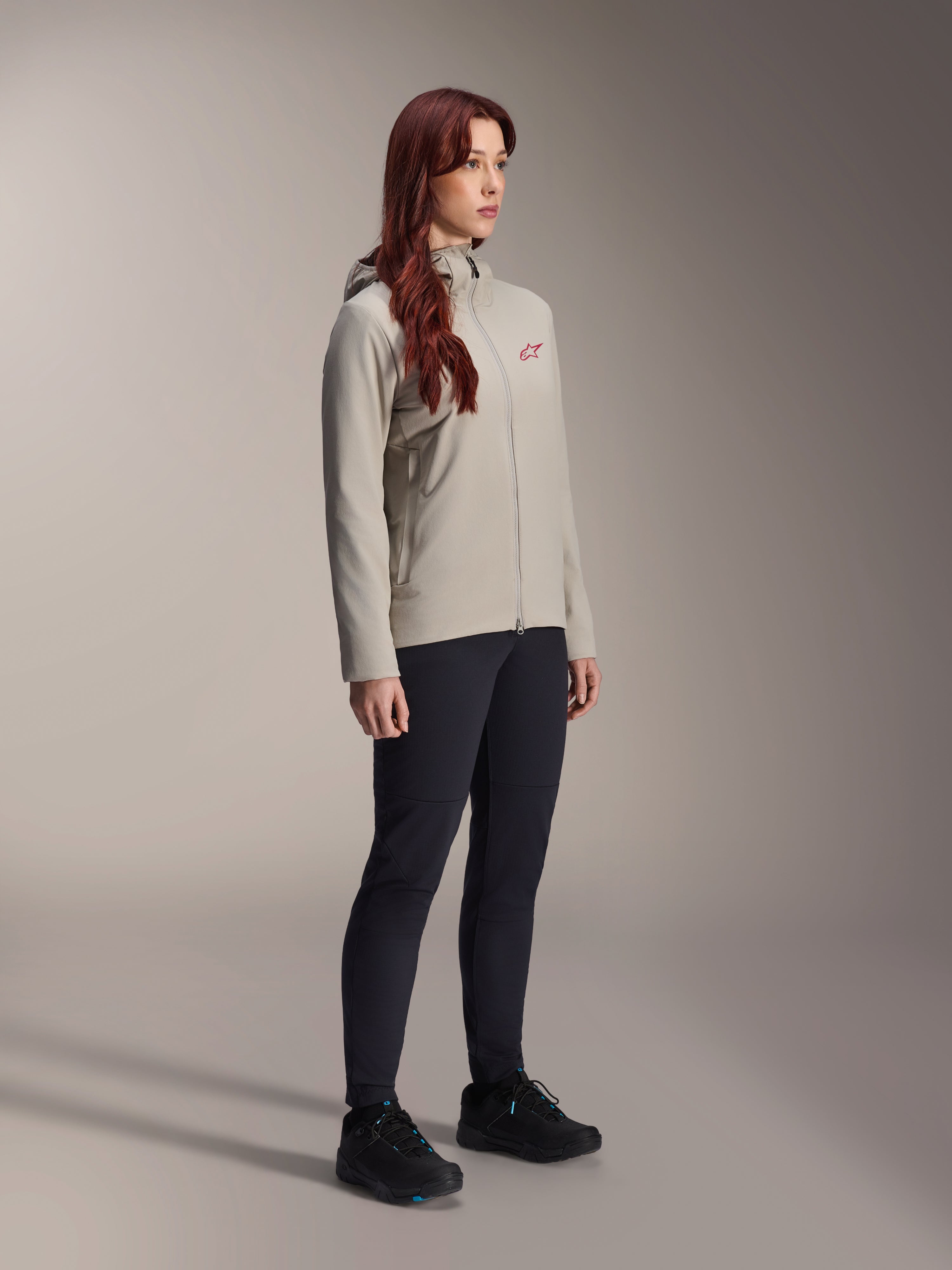 Alpinestars Stella A-Dura Thermal Jacket, szara damska kurtka rowerowa ocieplana, czerwone logo z gwiazdą na klatce piersiowej, czarne spodnie techniczne i czarne buty MTB, zdjęcie studyjne odzieży rowerowej