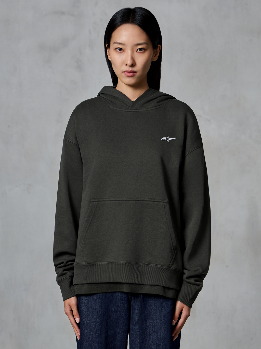 Alpinestars Essentials Ageless Hoodie, Off Black, worn by a model, featuring a small white Astars logo on the chest, front kangaroo pocket, stone-wash finish, casual premium fleece streetwear