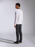 Alpinestars Bettern Crew, biała bluza typu crewneck, widok z tyłu i z boku, czarne okrągłe logo na rękawie, zestawiona z ciemnoszarymi spodniami i czarnymi sneakersami, casualowy motorsportowy styl streetwear