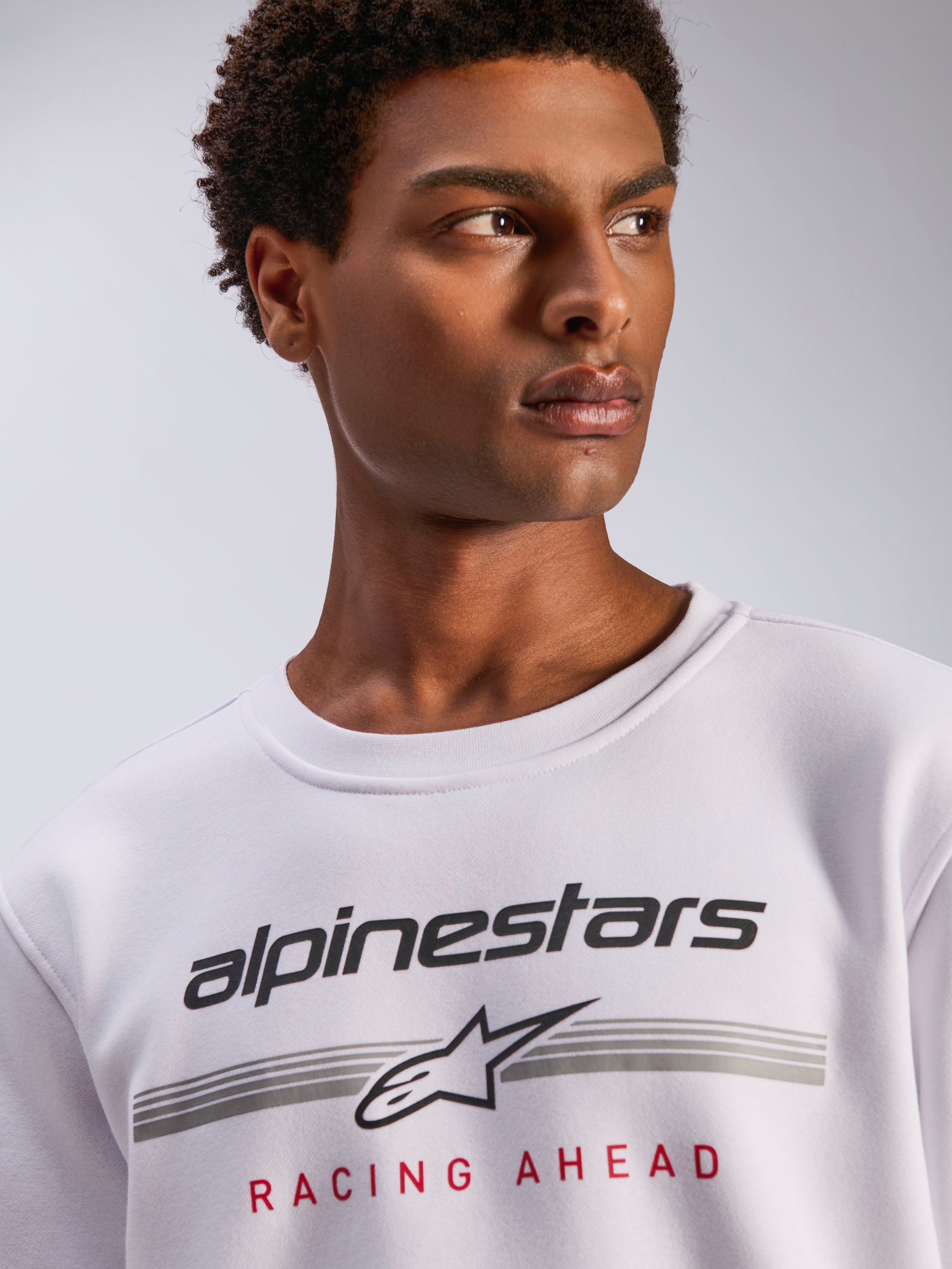 Alpinestars Bettern Crew, biała bluza typu crewneck z polaru, czarne logo Alpinestars z szarymi poziomymi liniami i czerwonym napisem „Racing Ahead”, codzienna odzież streetwearowa inspirowana sportami motorowymi