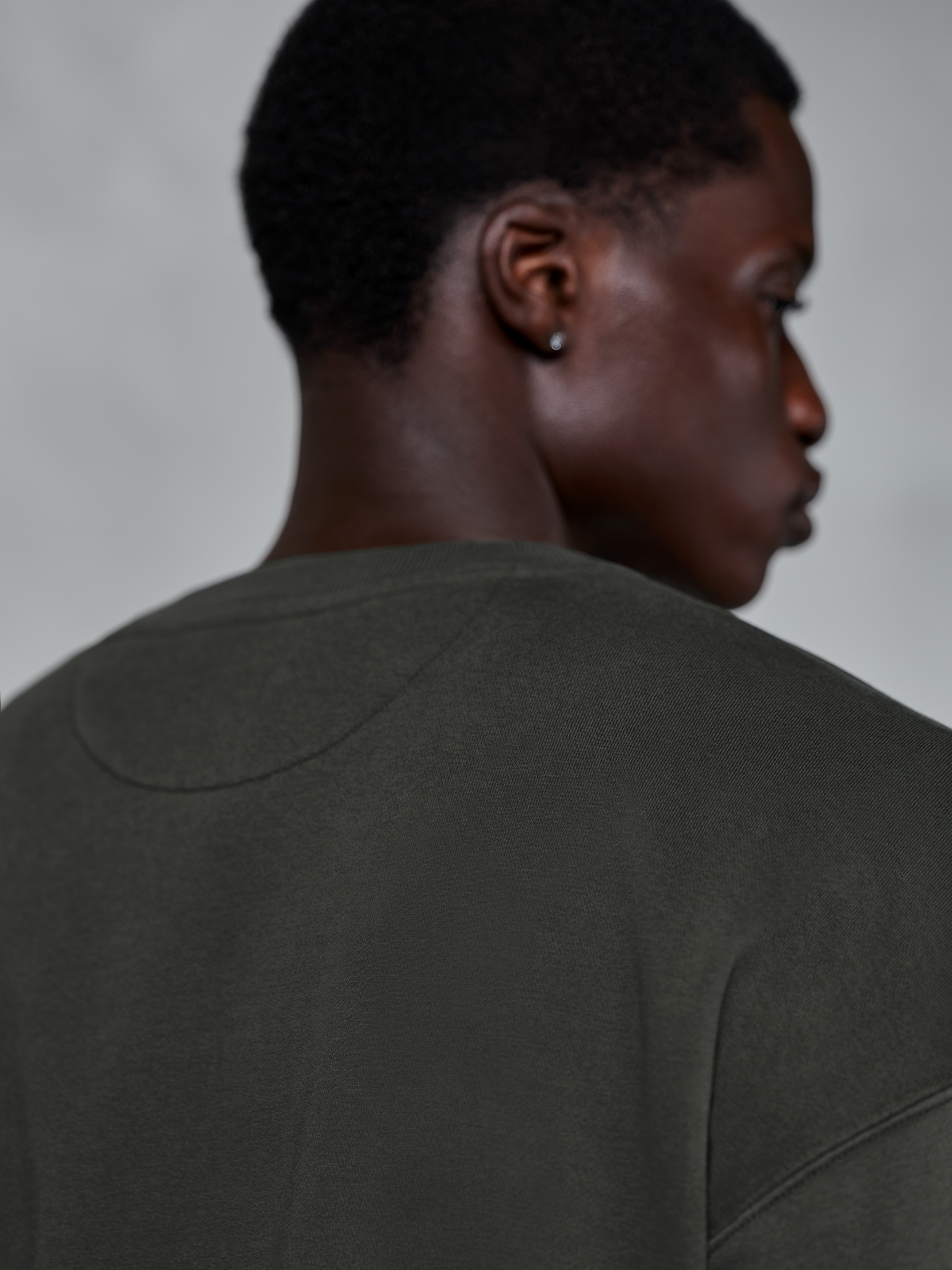 Alpinestars Essentials Ageless Crew, bluza z okrągłym dekoltem premium w kolorze Off Black, zbliżenie na tylny dekolt i obszar ramion, tekstura gęstego polaru wykończonego praniem kamiennym, casualowy styl streetwear inspirowany sportami motorowymi