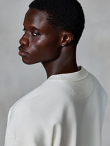 Alpinestars Essentials Ageless Crew, bluza z okrągłym dekoltem, kolor złamanej bieli, zbliżenie z tyłu na modelu prezentujące prążkowany dekolt i teksturę polaru premium, casual lifestyle streetwear