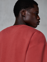 Alpinestars Essentials Ageless Crew, bluza z okrągłym dekoltem, ceglasta czerwień, zbliżenie na górną część pleców i kark, widoczny prążkowany kołnierzyk i tekstura polaru premium, codzienna odzież sportowa