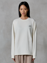 Alpinestars Essentials Ageless LS Tee, koszulka z długim rękawem, kolor złamanej bieli, z małym czarnym logo gwiazdy na piersi, luźny nowoczesny krój, dżersej z bawełny organicznej, codzienny streetwear inspirowany sportami motorowymi