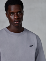 Alpinestars Essentials Ageless SS Tee, koszulka z krótkim rękawem, srebrna, z małym czarnym logo gwiazdy na piersi, prezentowana przez modela, codzienny styl streetwear