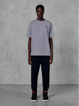 Alpinestars Essentials Ageless SS Tee, koszulka z krótkim rękawem, srebrna, z małym czarnym logo na piersi, zestawiona z czarnymi joggerami i sneakersami, codzienna odzież uliczna w stylu motorsport