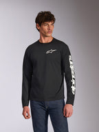 Alpinestars Trackside CSF Long Sleeve Tee, czarna, białe logo Alpinestars na piersi i branding na rękawie, prezentowana przez modela w niebieskich jeansach, codzienna odzież uliczna w stylu motorsport