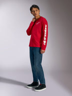 Alpinestars Trackside CSF Long Sleeve Tee, Red with white Alpinestars branding on chest and sleeve, worn by model with blue jeans and black sneakers, casual motorsport-inspired streetwear