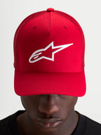 Alpinestars Ageless Snapback Hat, czerwona czapka z daszkiem ze sportowym, usztywnionym panelem, haftowanym białym logo Astars i zakrzywionym daszkiem, prezentowana na modelu