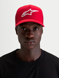 Alpinestars Ageless Snapback, czerwona czapka z daszkiem noszona przez modela, z białym wypukłym haftem 3D z logo Astars, zakrzywionym daszkiem i usztywnioną koroną z bawełnianego kepru