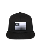 Alpinestars Flag Flat Trucker Hat, czarna czapka z płaskim daszkiem i usztywnioną koroną, centralna prostokątna naszywka z białą flagą i logo Alpinestars, tył z siatki, casualowa odzież streetwearowa inspirowana motorsportem