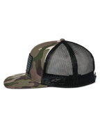Alpinestars Flag Flat Trucker Hat, zielony kamuflaż i czarny, płaski daszek i usztywniona korona, przód z tkaniny twill w kamuflażu i czarna siatka z tyłu, widok z boku pokazujący naszywkę z flagą i haftowane logo, codzienna odzież uliczna inspirowana sportami motorowymi