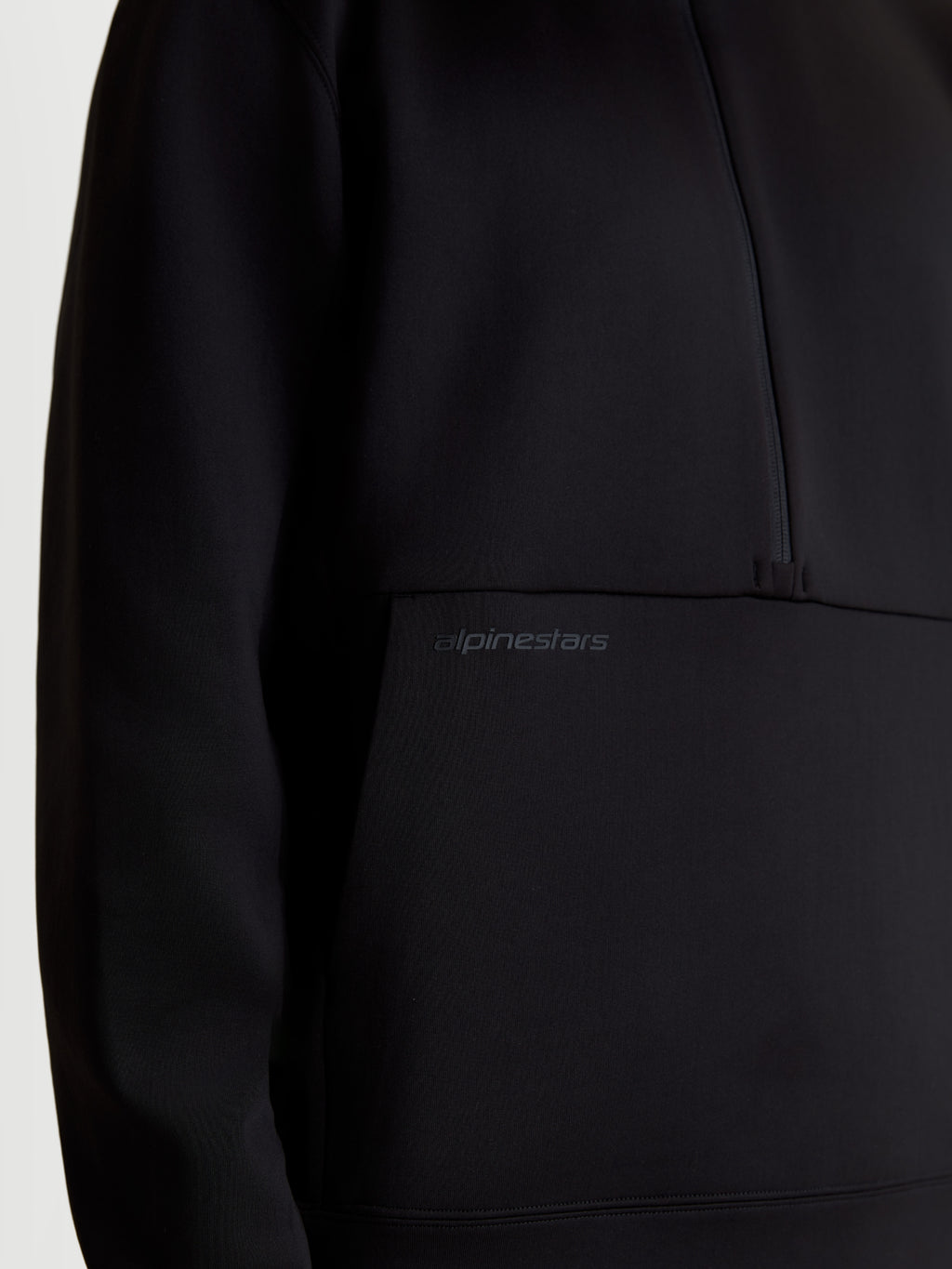Alpinestars Bluza Apera Half-Zip, sportowa bluza typu pullover dla mężczyzn i kobiet, czarna, zbliżenie na tonalny nadruk logo HD na kieszeni kangurce i zamek 1/2, konstrukcja z polaru tri-blend premium.