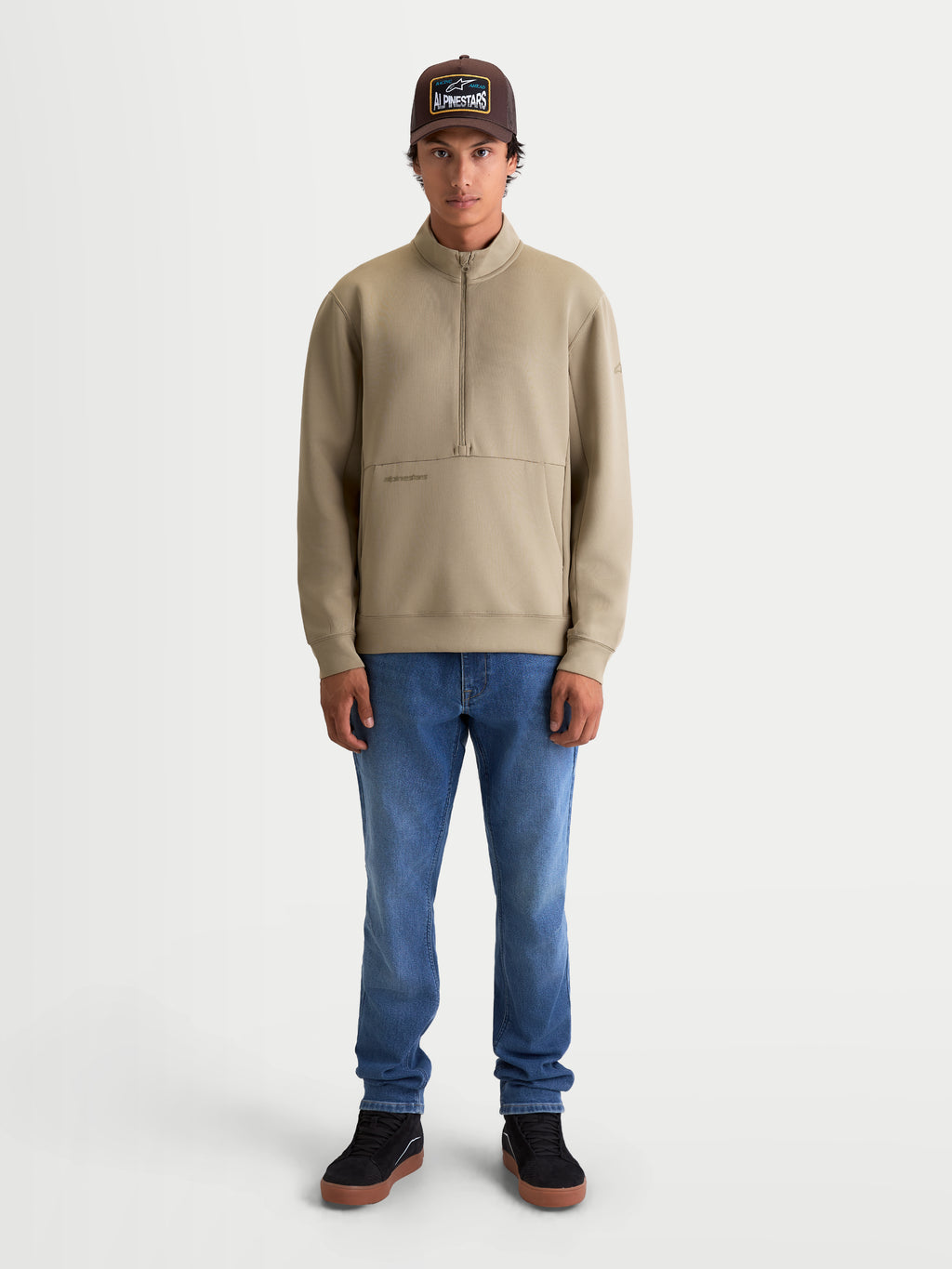 Alpinestars bluza Apera z półzamkiem, męska beżowa bluza sportowa typu pullover, polar tri-blend z kieszenią kangurką i zapięciem na półzamek, casualowy styl motorsportowy, model prezentujący produkt.