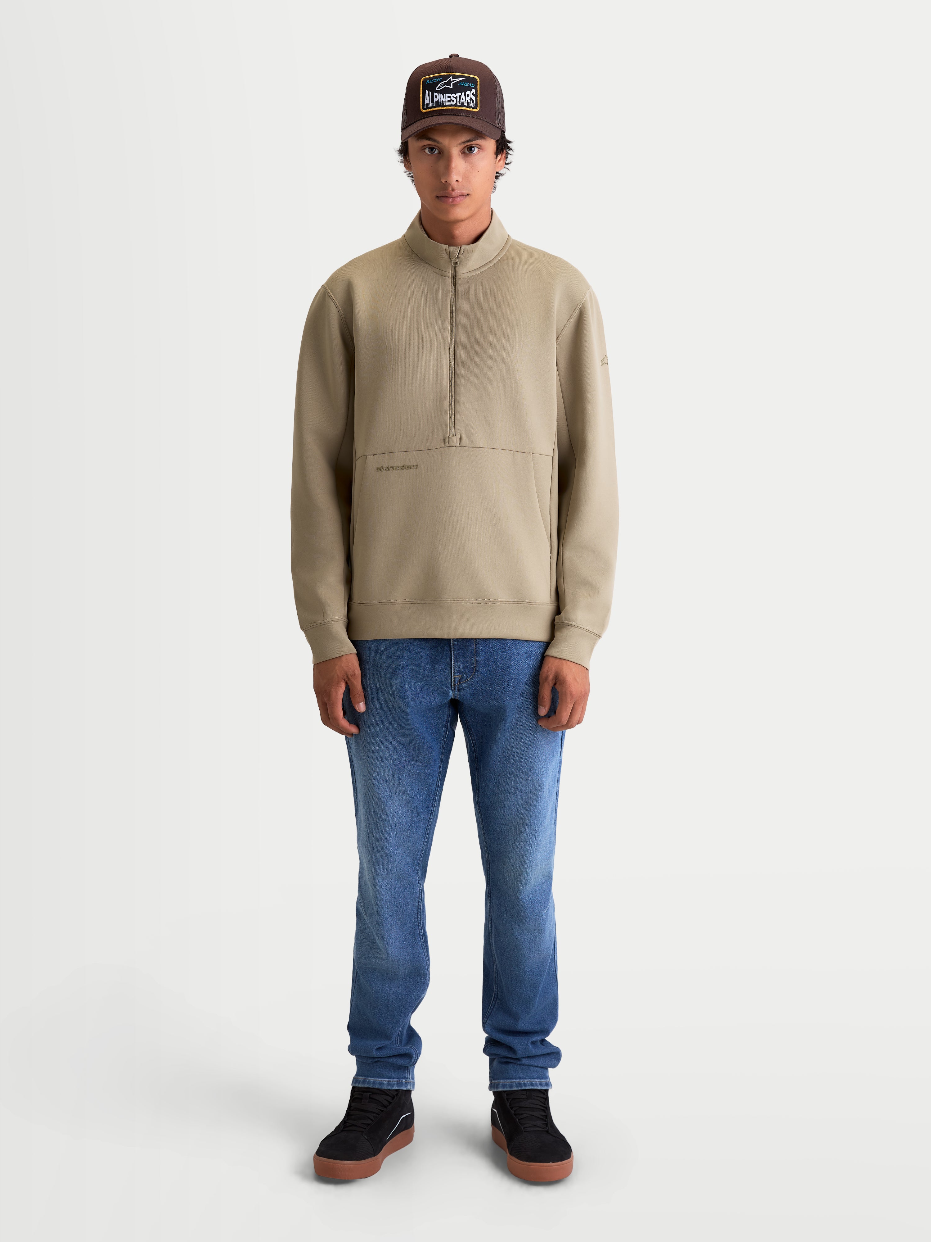 Alpinestars bluza Apera z półzamkiem, męska beżowa bluza sportowa typu pullover, polar tri-blend z kieszenią kangurką i zapięciem na półzamek, casualowy styl motorsportowy, model prezentujący produkt.