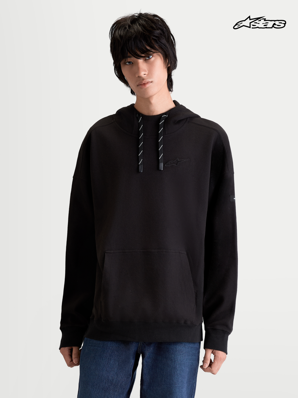 Alpinestars Camino Textured Oversized Hoodie, czarna bluza z kapturem w stylu sportswear na modelce, z teksturowanego polaru dzianinowego twill z kieszenią kangurką i wysokim kołnierzem