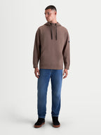 Alpinestars Bluza Z Kapturem Camino Textured Oversize, męska brązowa bluza sportowa typu pullover, teksturowany polar dzianinowy o splocie twill, wysoki kołnierz z regulowanymi sznurkami i kieszeń kangurka, luźny fason oversize, model na neutralnym tle.