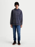Alpinestars bluza z kapturem Infinite Washed Oversized, casualowa bluza sportowa typu pullover noszona przez modela, granatowa z wykończeniem snow-wash, kieszeń kangurka i haftowany napis Alpinestars na klatce piersiowej, bawełna premium i poliester z recyklingu, krój oversize zapewniający komfort.