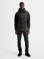 Alpinestars bluza z kapturem Infinite Washed Oversized, sportowa bluza o luźnym kroju, kolor spierany czarny z wykończeniem snow-wash, haftowane techniczne logo na piersi, kieszeń kangurka, casualowa odzież lifestyle, widoczna na modelu.