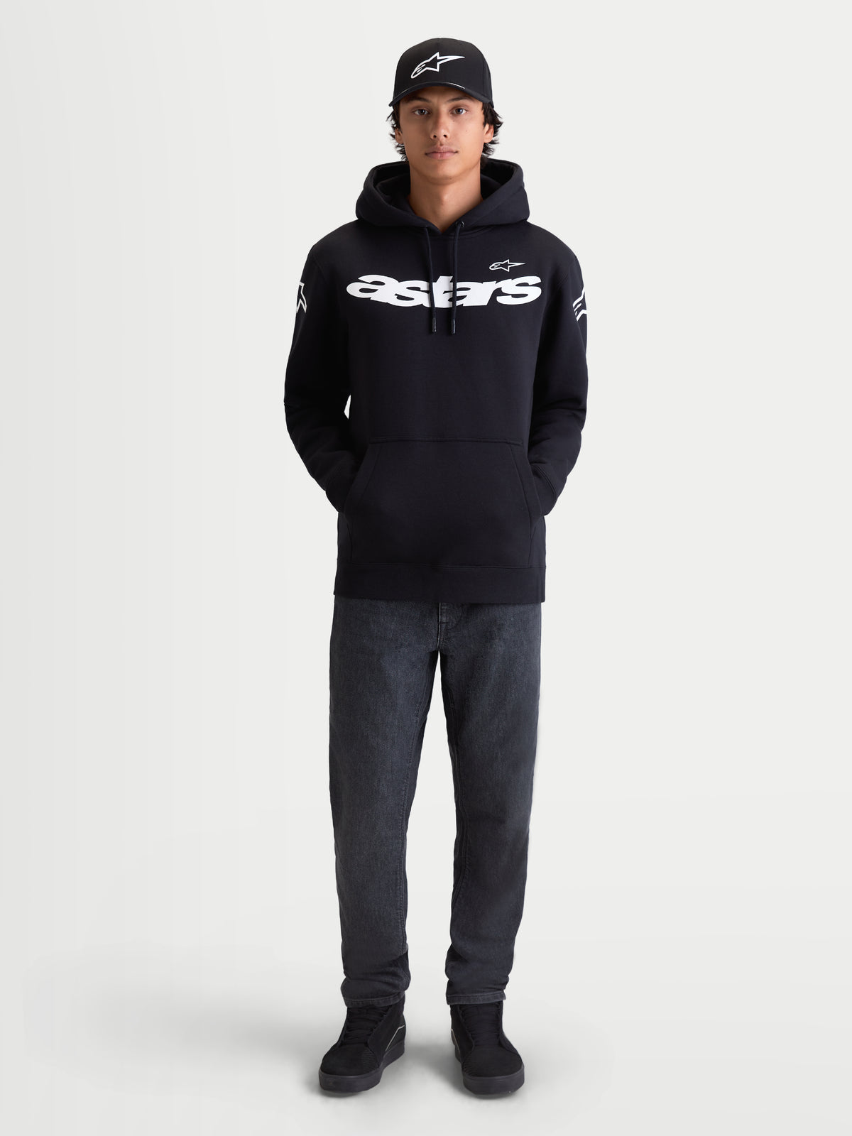 Alpinestars bluza z kapturem Velocifier, męska czarna bluza typu pull-over, biały logotyp Astars na piersi i logo na ramionach, premium mieszanka bawełny, casualowa odzież sportowa, zaprezentowana na modelu z czarną czapką z daszkiem.