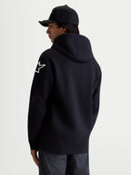 Alpinestars Bluza z kapturem Velocifier, męska czarna bluza typu pullover, białe logo Astars na ramieniu, widok z tyłu na modelu, mieszanka bawełny i poliestru z recyklingu, codzienna odzież sportowa dla fanów motorsportu.