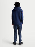 Alpinestars Bluza z kapturem Velocifier, granatowa polarowa bluza typu pullover z czerwonymi logotypami na ramionach, widok z tyłu na modelu, mieszanka bawełny i poliestru z recyklingu, odzież sportowa w stylu casualowym.