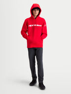 Alpinestars Bluza z kapturem Race Wordmark, męska bluza z polarem, czerwona i biała, wyrazisty liniowy napis na piersi i logo Ageless na rękawie, model w bluzie z założonym kapturem, codzienna odzież inspirowana motorsportem.