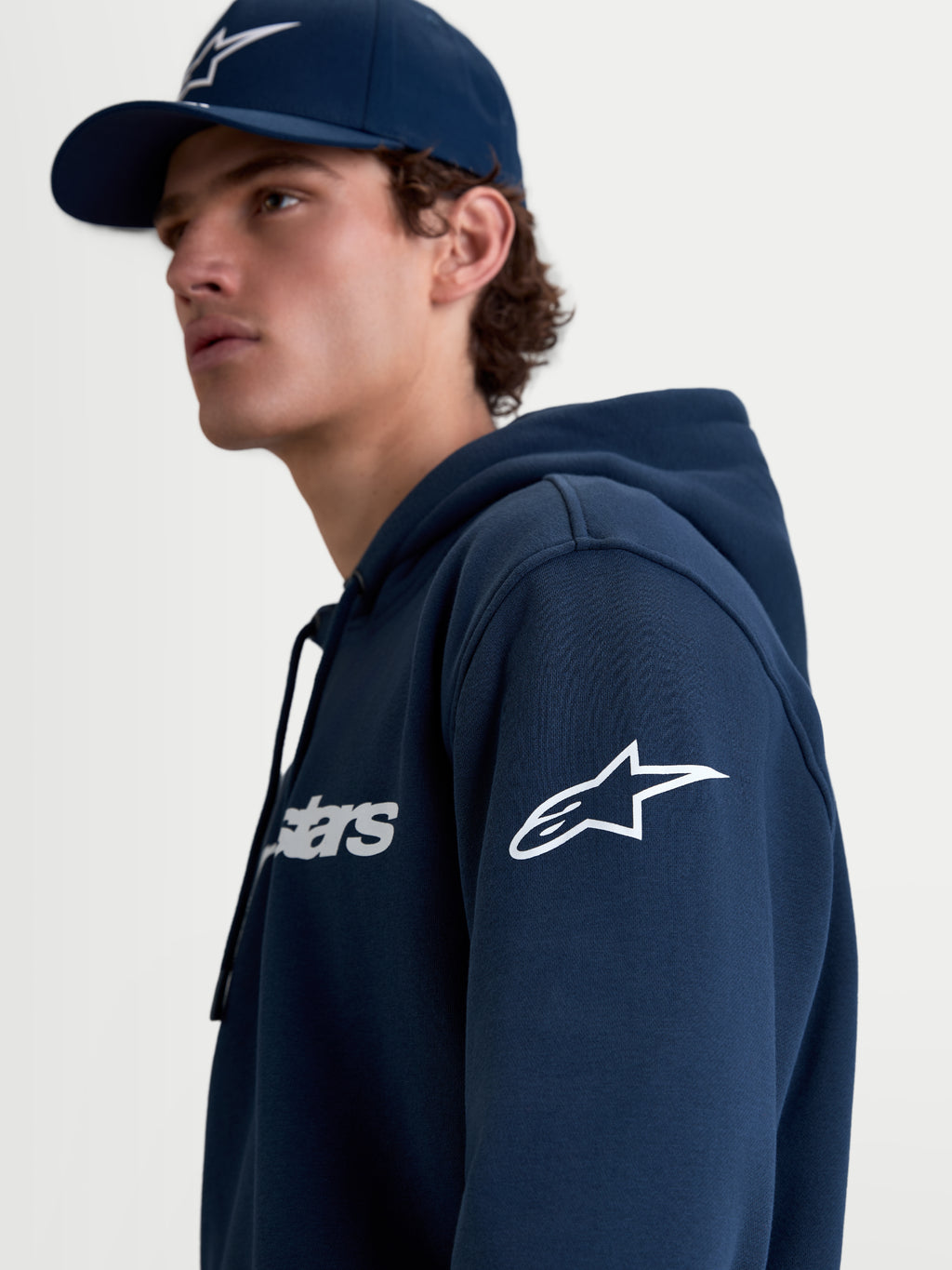Alpinestars bluza z kapturem Race Wordmark, męska bluza sportowa typu polar, niebieska i biała, białe logo Ageless na rękawie i napis Race Wordmark na piersi, lifestylowy widok na modelu.