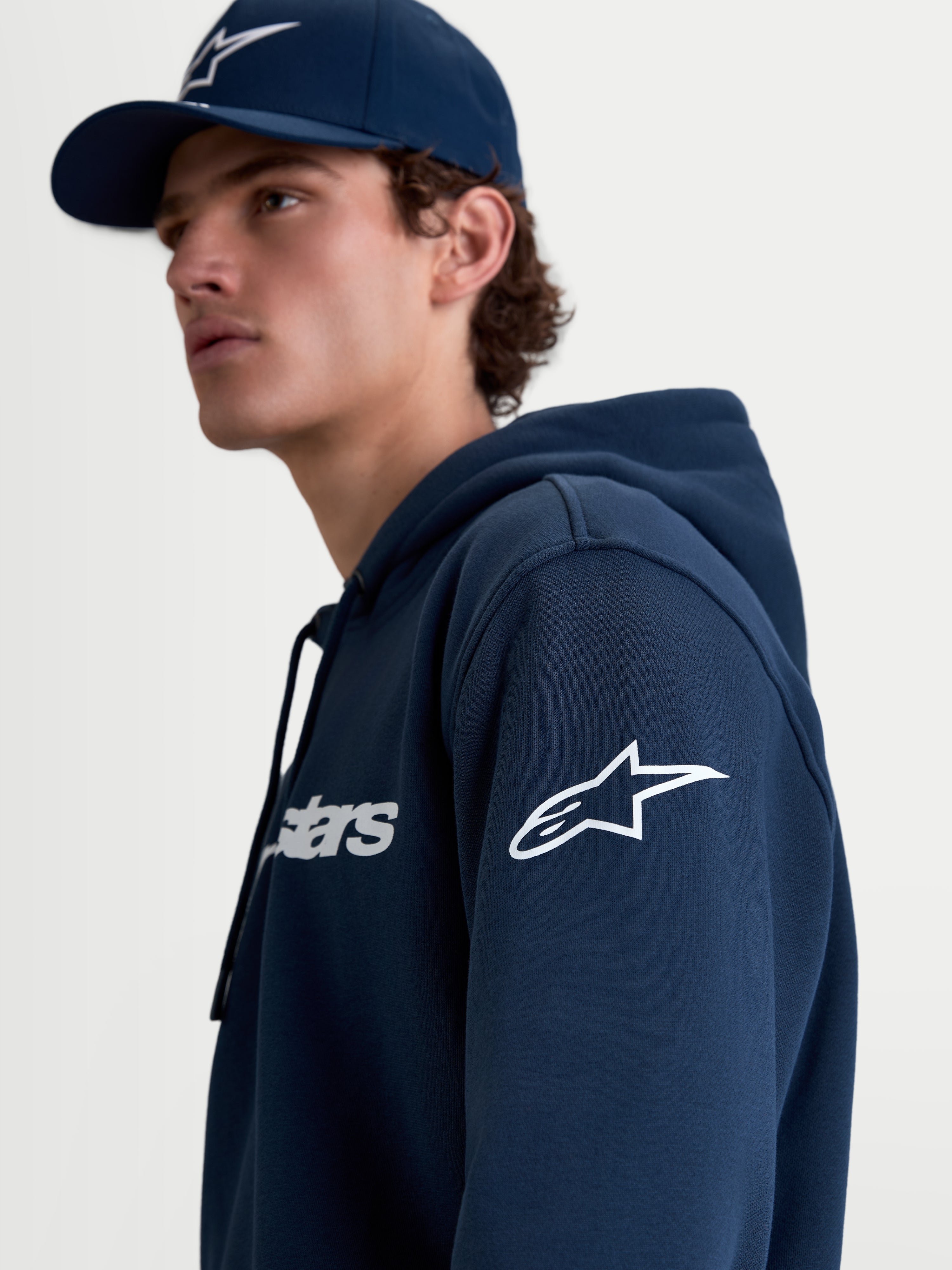 Alpinestars bluza z kapturem Race Wordmark, męska bluza sportowa typu polar, niebieska i biała, białe logo Ageless na rękawie i napis Race Wordmark na piersi, lifestylowy widok na modelu.