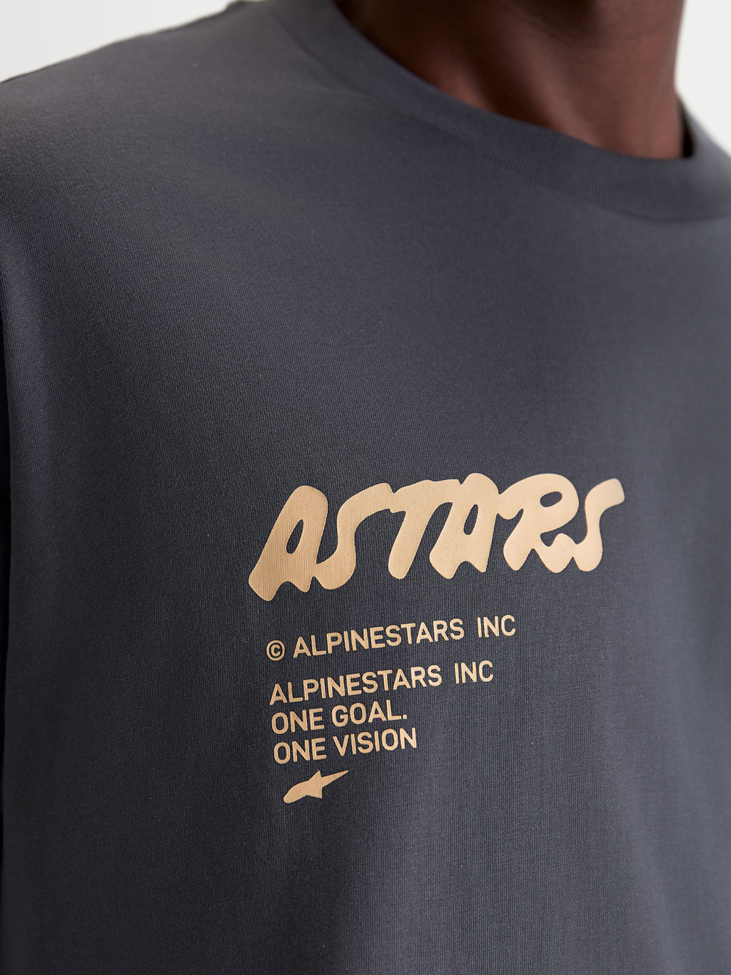 Alpinestars Chalk Oversized CSF Tee, Unisex Sportswear Short Sleeve T-Shirt, Charcoal Gray with Cream Graphic, Close-up detail of front chest logo featuring Astars branding and One Goal One Vision manifesto, premium cotton-poly blend.