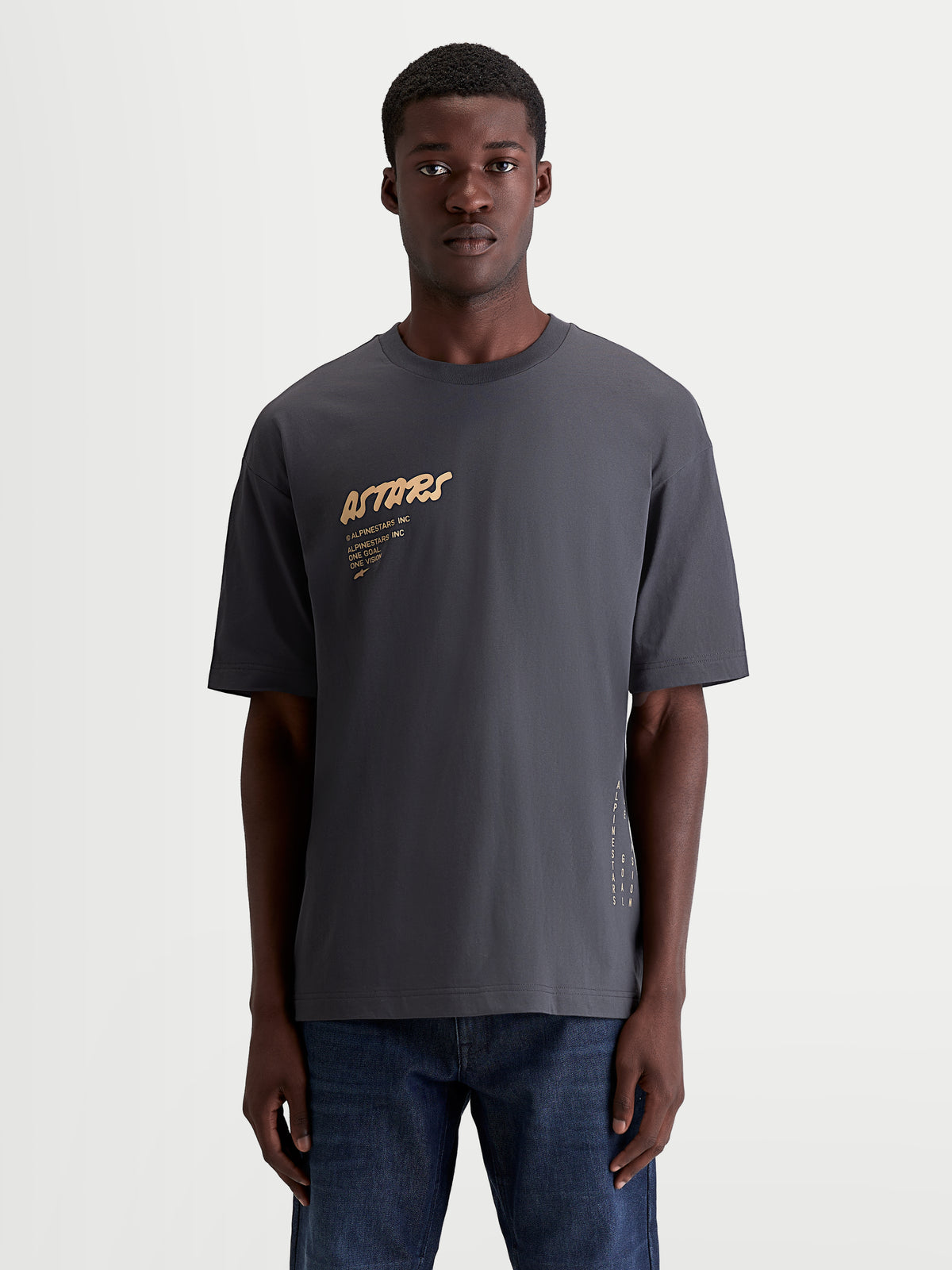 Alpinestars Koszulka Chalk Oversized CSF, grafitowa koszulka z krótkim rękawem, piaskowe logo Astars na piersi i branding z boku, luźny fason oversize, odzież sportowa, mieszanka bawełny i poliestru, widoczna na modelu