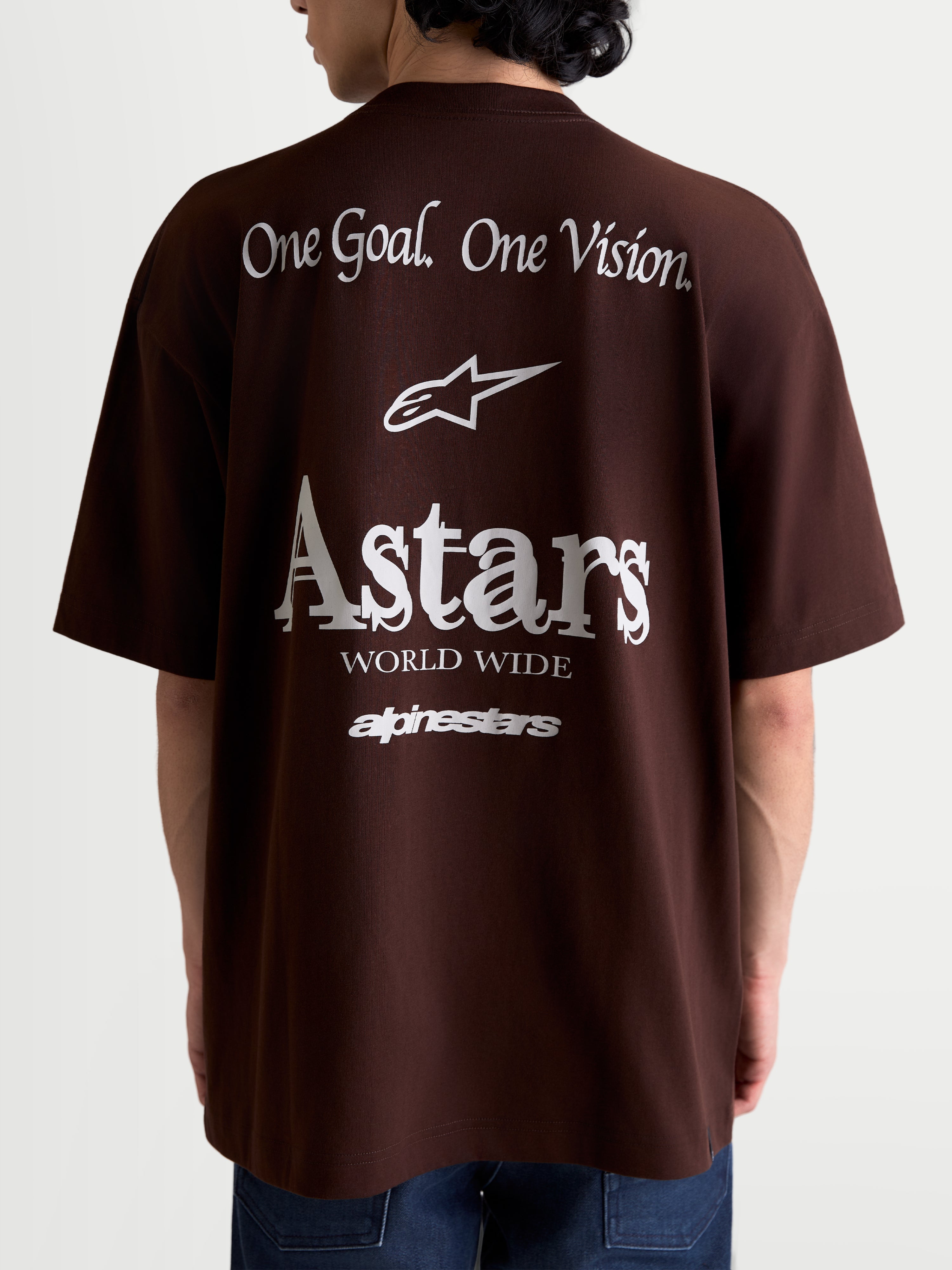 Alpinestars Koszulka Post Oversized CSF, brązowa koszulka z krótkim rękawem, widok z tyłu na modelu, białe grafiki One Goal. One Vision. oraz Astars World Wide, swobodny krój oversize