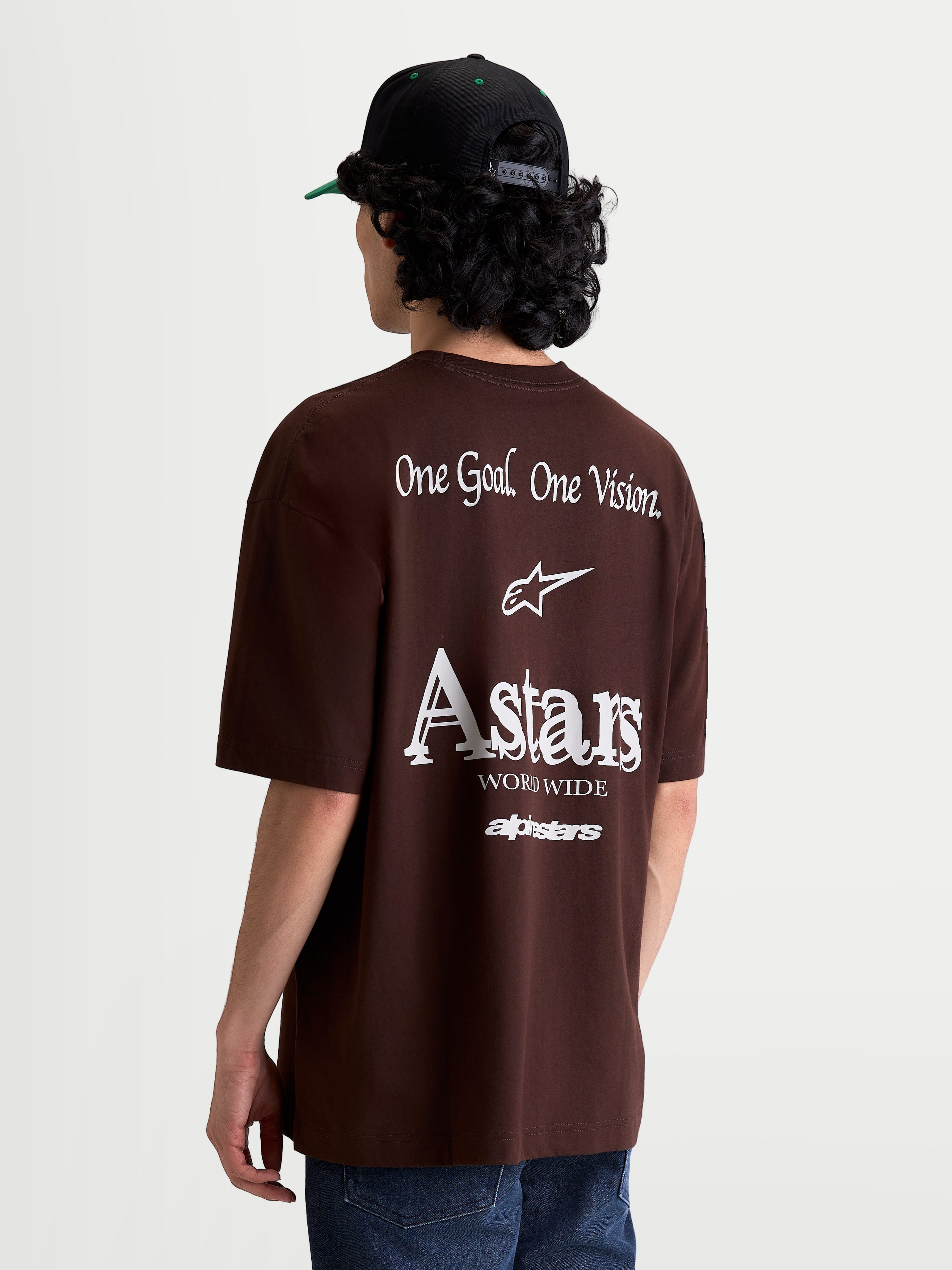 Alpinestars Koszulka Post Oversized CSF, brązowy t-shirt sportowy z krótkim rękawem, widok z tyłu na modelu z białą grafiką brandingową One Goal. One Vision. i Astars, krój oversized, casualowa odzież z mieszanki bawełny i poliestru.