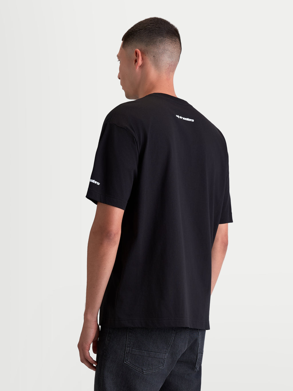 Alpinestars Mandate Oversized CSF, męska czarna koszulka z krótkim rękawem, widok z tyłu, białe logotypy na karku i rękawie, luźny krój oversize, casualowa odzież sportowa.