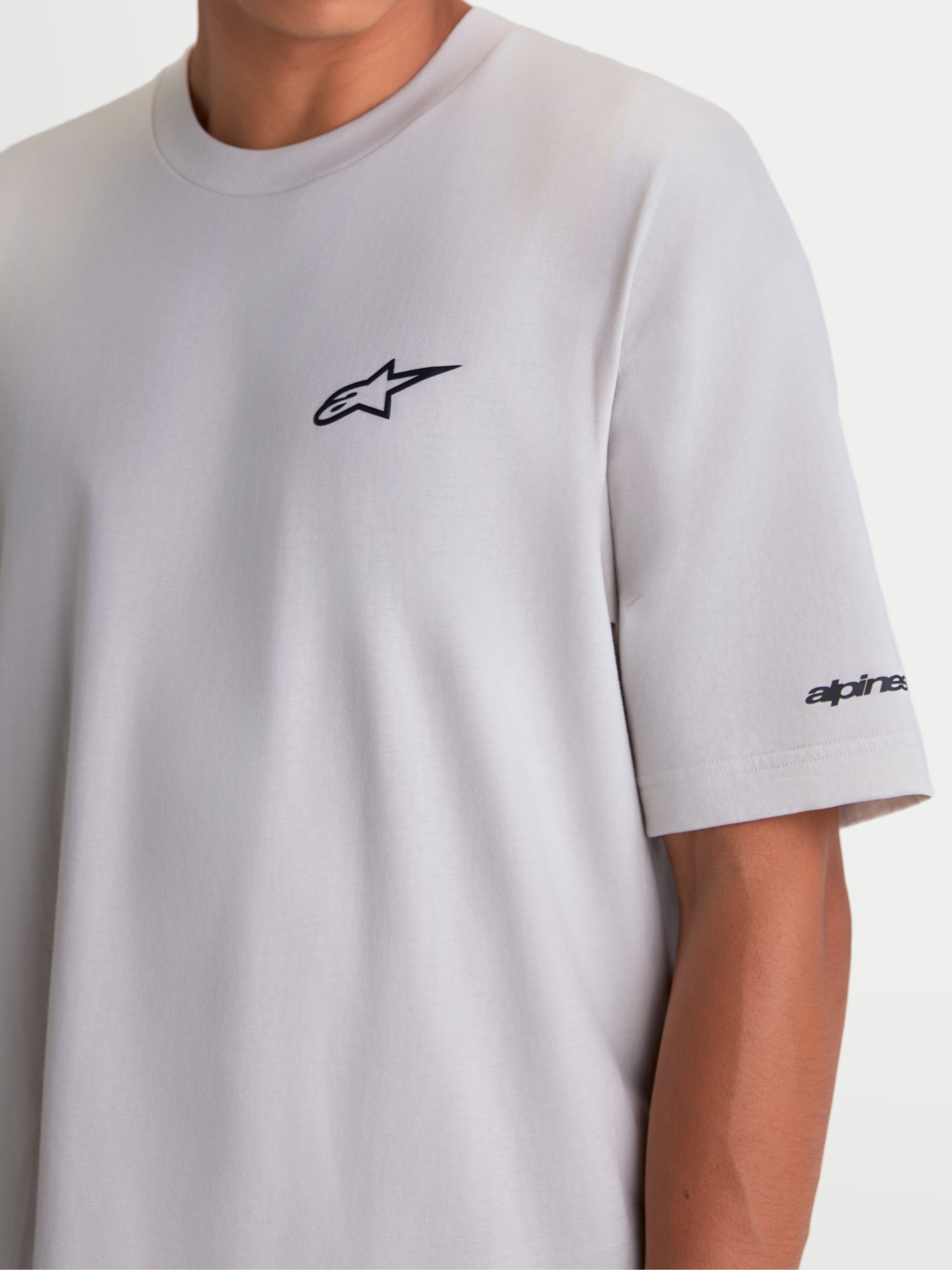 Alpinestars Koszulka Mandate Oversized CSF, szara koszulka z krótkim rękawem, krój oversize, czarne wypukłe logo Astars na piersi i grafika na rękawie, casualowa odzież sportowa.