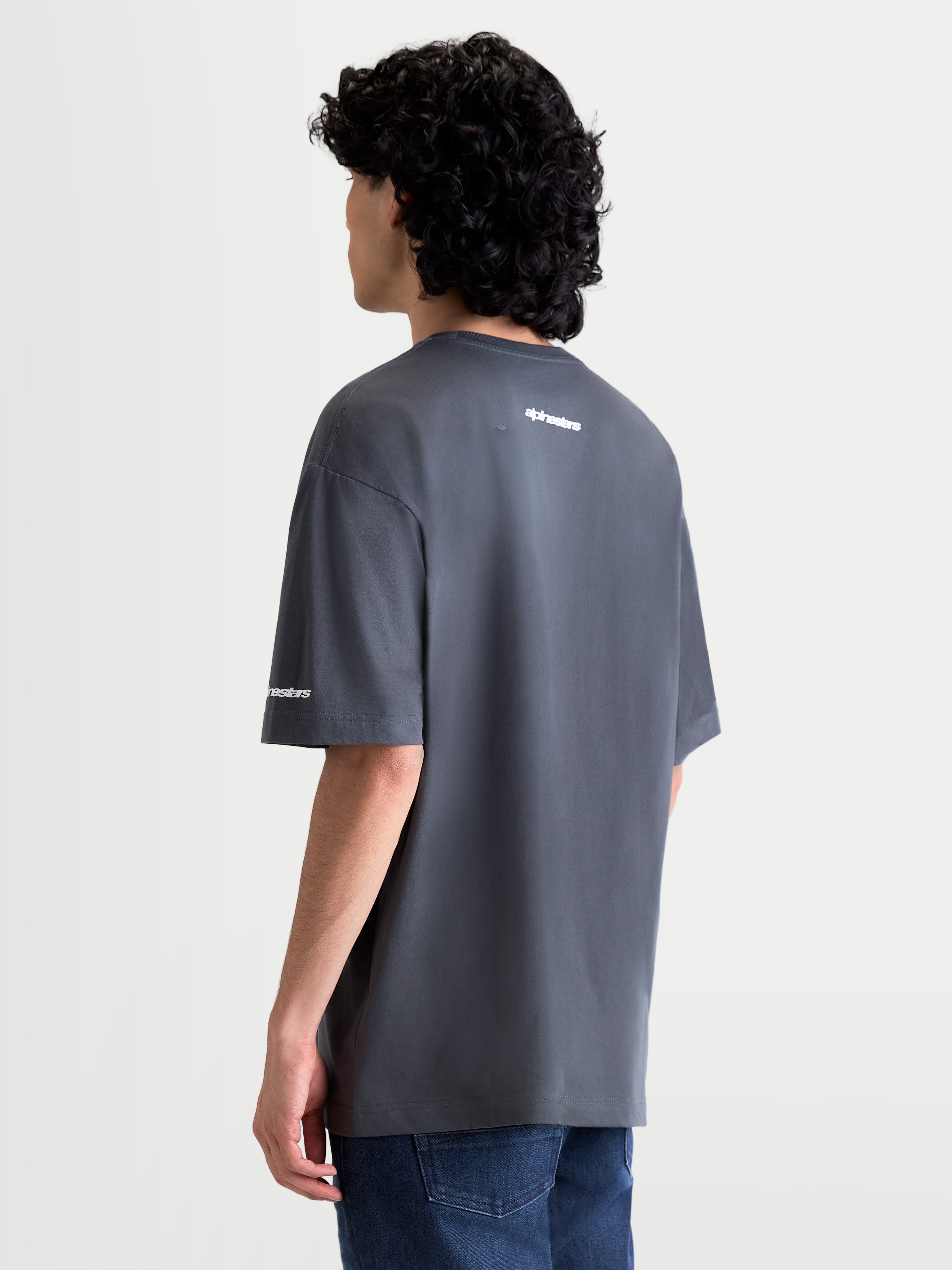 Alpinestars Mandate Oversized CSF Tee, Casual Sportswear Short Sleeve T-Shirt, Charcoal Gray, white puff-print logo on back and sleeve, oversized relaxed fit silhouette, cotton-poly blend fabric, on-model view from the back.