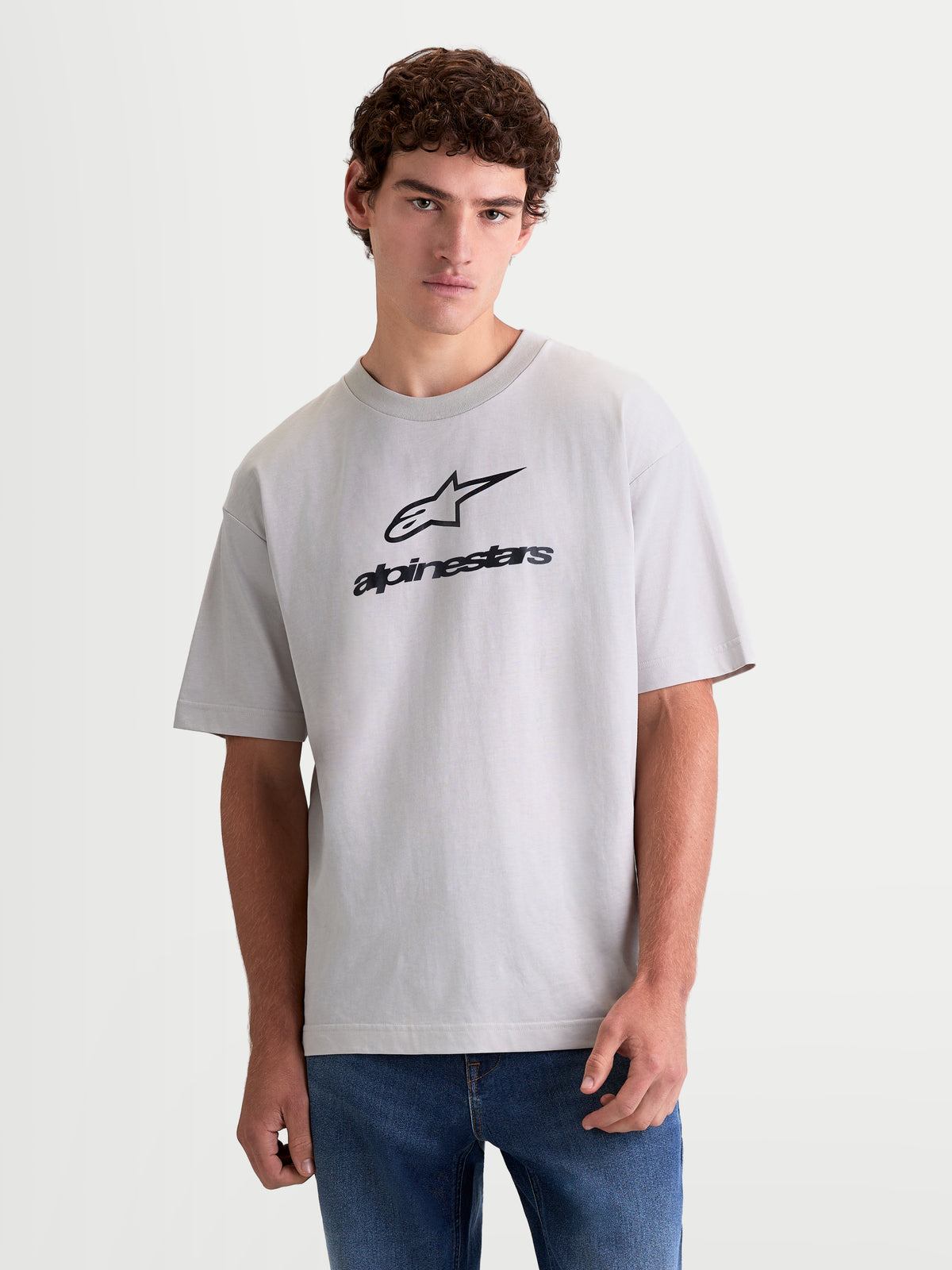 Alpinestars Prelude Oversized CSF, szara koszulka z krótkim rękawem, czarne logo na klatce piersiowej, krój oversize, codzienna odzież sportowa, widok z przodu na modelu.