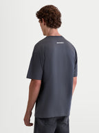 Alpinestars Koszulka Prelude CSF Oversize, męska koszulka sportowa z krótkim rękawem w kolorze szarym, widok z tyłu z białą grafiką logo Alpinestars, luźny krój oversize do noszenia na co dzień.