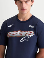 Alpinestars Koszulka Cypress CSF, męska koszulka z krótkim rękawem, granatowa i biała, grafika Astars z siatkowym wypełnieniem i logo na klatce piersiowej, napis Alpinestars Protects, mieszanka bawełny i poliestru, zbliżenie na modela.