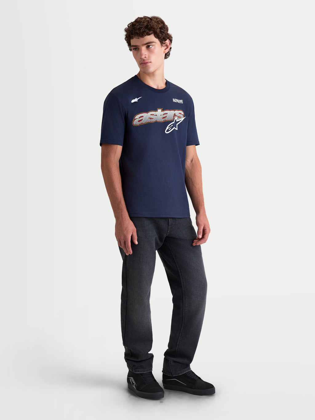 Alpinestars koszulka Cypress CSF, męska koszulka z krótkim rękawem na modelu, granatowa, frontowa grafika Astars Word z siatkowym wypełnieniem, białe i pomarańczowe detale, codzienna odzież sportowa.